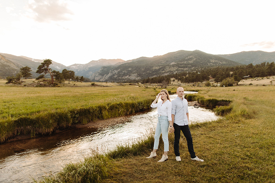 couple stands by a creek in the Rocky Mountains