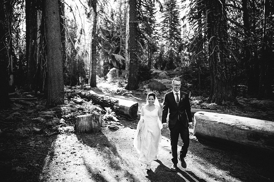 bride and groom walking through the forest
